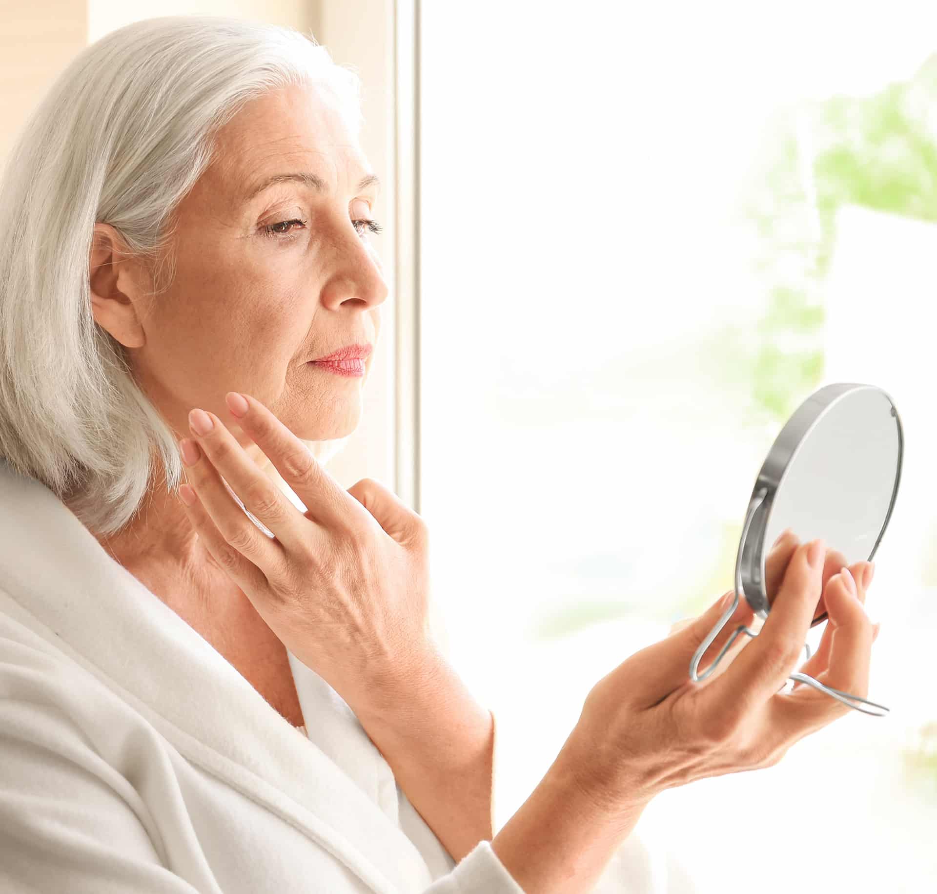 elder woman looking into a mirror after cosmetic skin treatment at rocklin dermatology