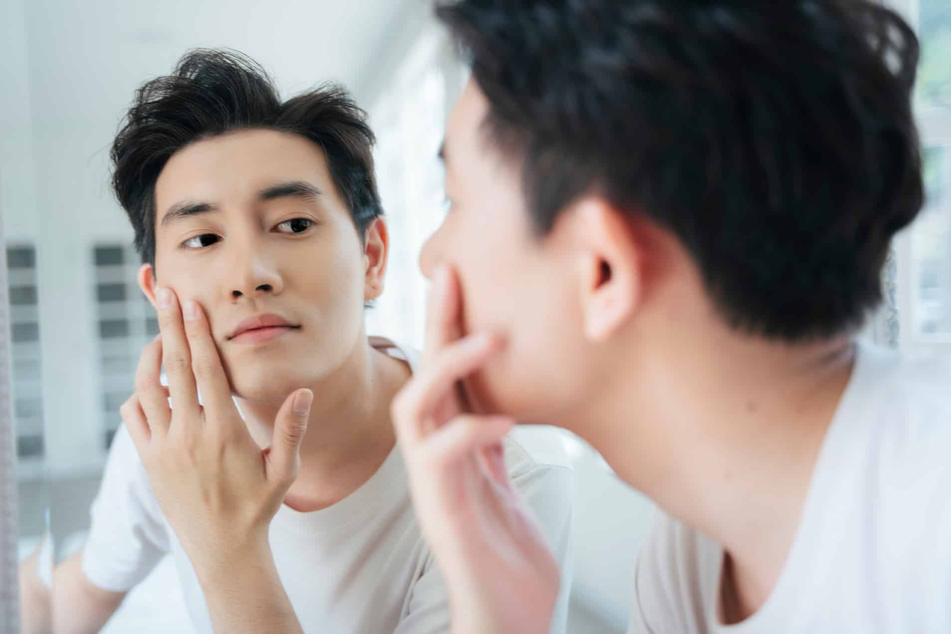 man looking in a mirror after medical dermatology treatment at rocklin dermatology